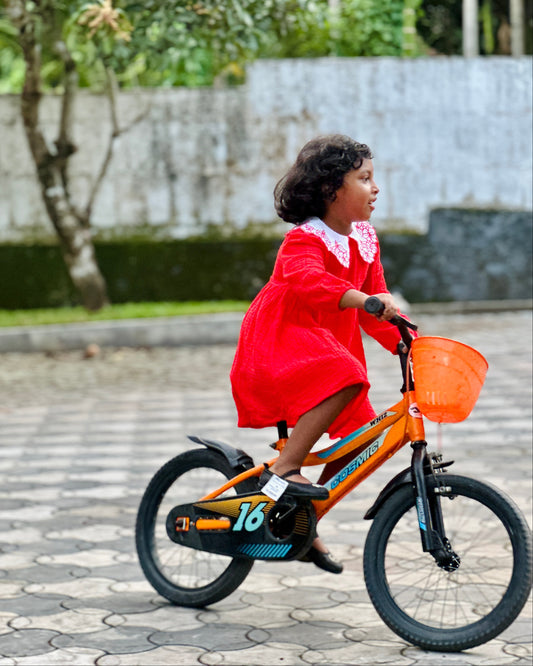 Girl in comfortable red dress riding a bike